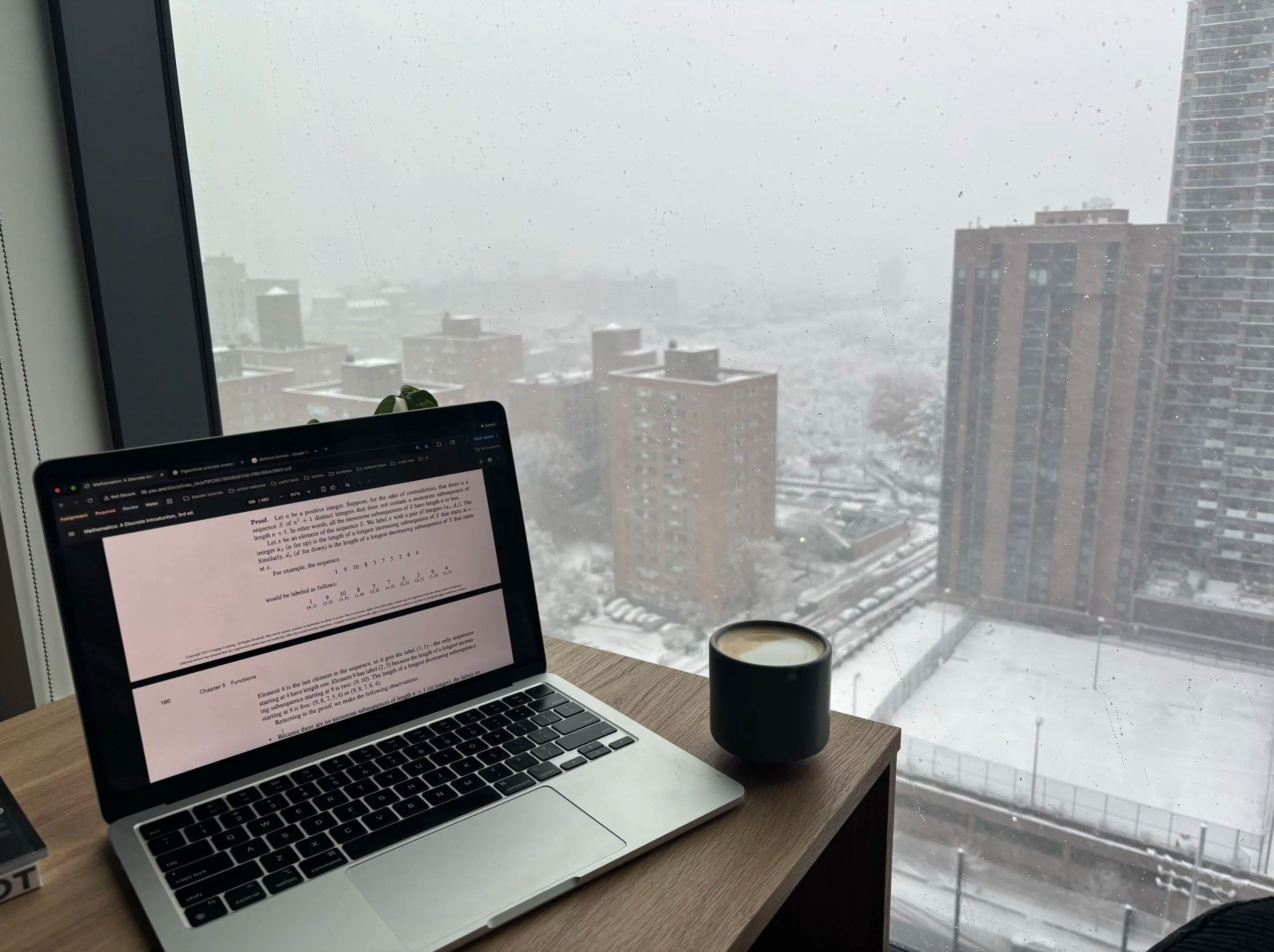 A laptop and coffee on a desk overlooking a snowy city