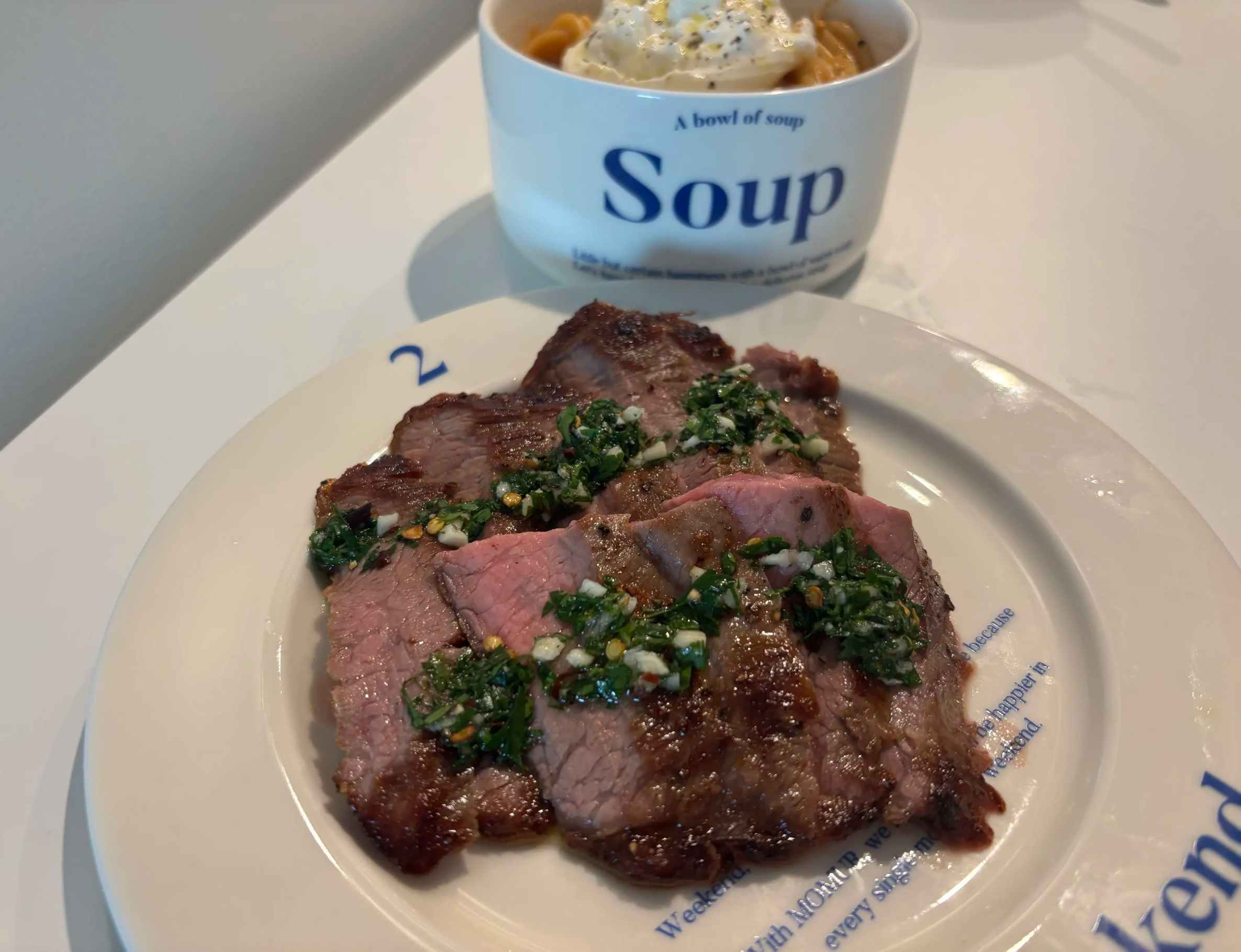 A sliced steak with chimichurri, plated at a restaurant